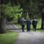 Clarke University students accompany sisters in wheelchairs and walkers to the Mount Carmel cemetery to visit their dear friends.